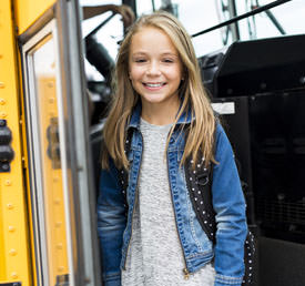 student standing in front of school bus doors